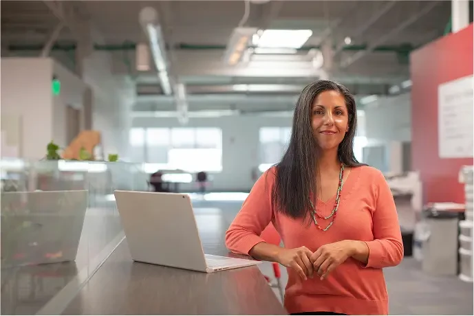 Consultora sorrindo ao lado de um notebook